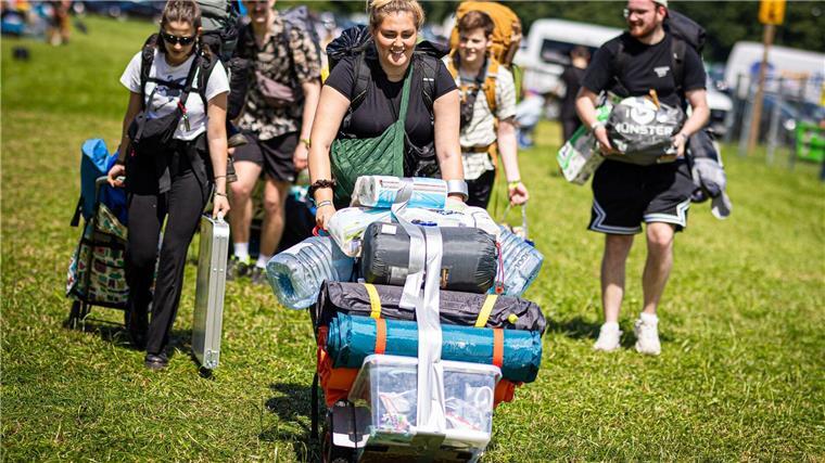Festivalbesucher kommen mit ihrem Gepäck am Zeltplatz an.
