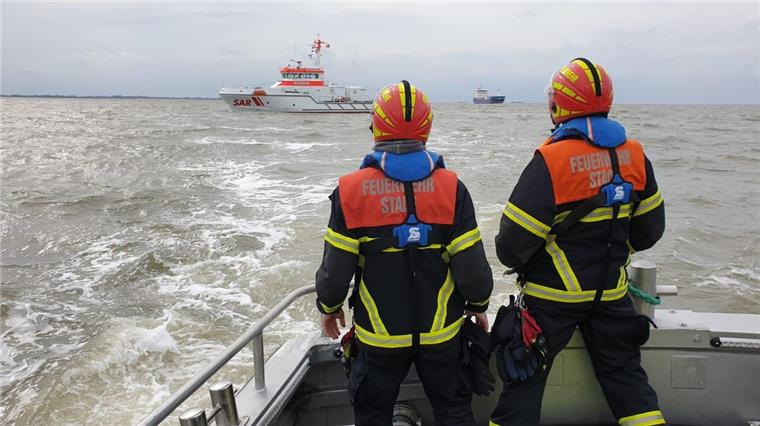 Feuerwehrleute auf der "Henry Köpcke" blicken auf die Einsatzstelle.