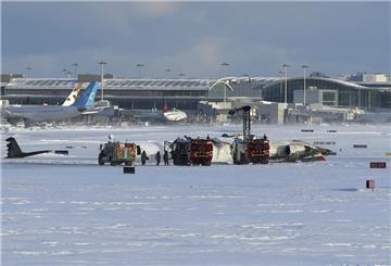 Feuerwehrleute des internationalen Flughafens Pearson arbeiten an einem auf dem Rücken liegenden Flugzeug der Delta Air Lines, das auf dem Weg von Minneapolis nach Toronto war, als es auf der Landebahn umstürzte.