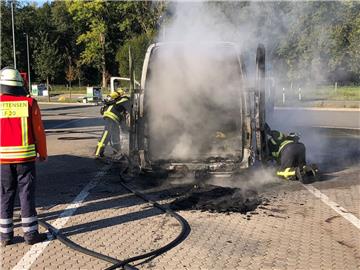 Feuerwehrleute untersuchen den ausgebrannten Lieferwagen auf versteckte Glutnester.