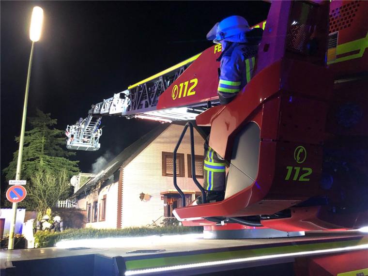 Feuerwehrmänner decken Teile des Daches ab, um zu schauen, ob sich dort Glutnester verbergen.