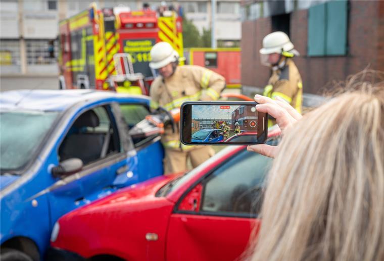 Eine Gafferin filmt Rettungskräfte beim Einsatz am Unfallort. Nachgestellte Szene. 