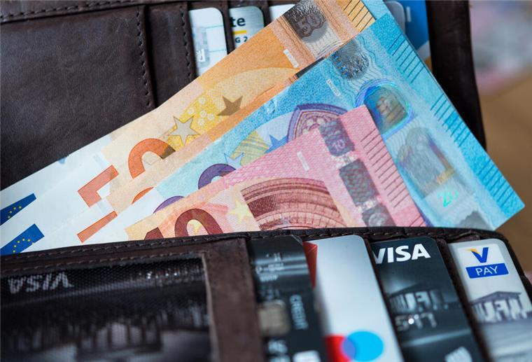 Zahlreiche Banknoten und Bankkarten liegen in einer geöffneten Geldbörse. 