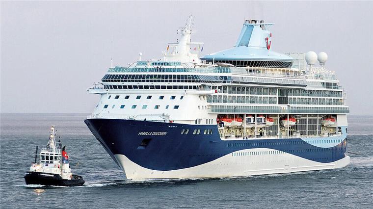 Kooperation mit Fincantieri: TUI-Tochter Marella Cruises plant erste Neubauten Ein Schlepper (links) begleitet ein blau-weißes Kreuzfahrtschiff. Fincantieri und TUI haben eine Absichtserklärung für zwei neue Kreuzfahrtschiffe unterzeichnet.