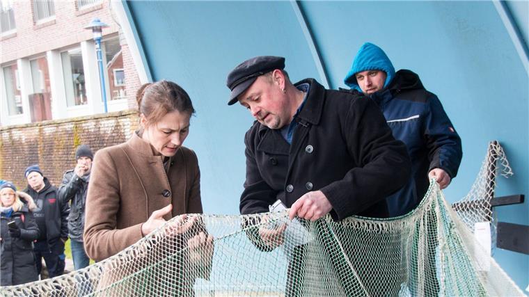 Grundschleppnetzverbot: Ministerin unterstützt Küstenfischer Fischer Nils Sander (M) zeigt Miriam Staudte (Bündnis 90/Die Grünen, l), Landwirtschaftsministerin von Niedersachsen, nach einem Treffen im Hafen Maschengrößen eines Netzes.