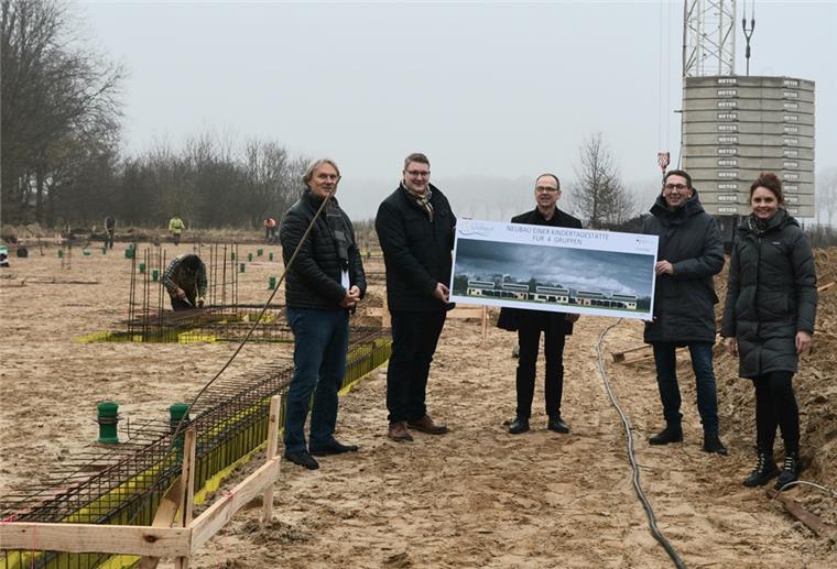 Spaden: Startschuss für den langersehnten Kitabau Eine Menschengruppe hält ein Plakat auf einer Baustelle hoch.
