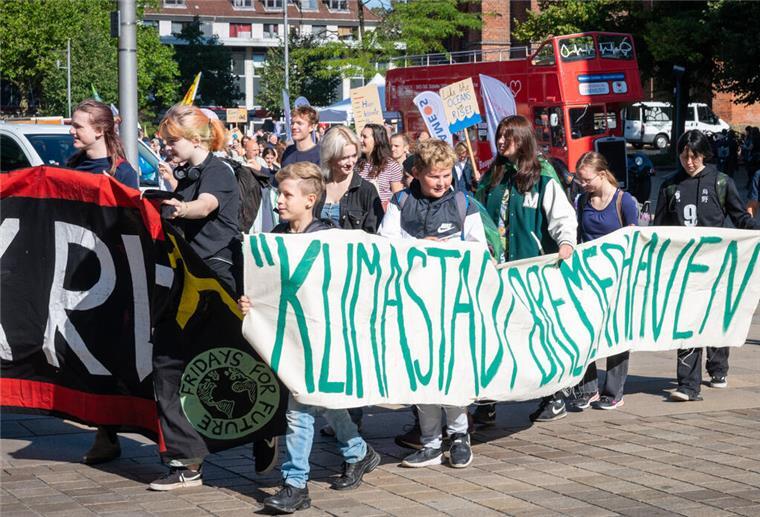 Fridays for Future: So lief der Klimastreik in Bremerhaven Eine Teilnehmerin eines Protestzugs der Klimabewegung Fridays for Future trägt ein Pappschild mit einer Darstellung, auf der ein Radfahrer ein Auto in einer Mülltonne entsorgt. Die Demonstration durch Lüneburg soll unter anderem auf die Notwendigkeit der Bahn-Neubaustrecke Hamburg-Hannover aufmerksam zu machen. +++ dpa-Bildfunk +++
