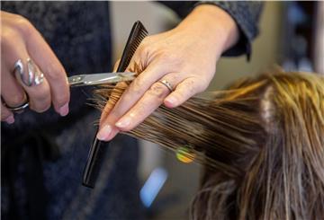Eine Friseurin schneidet einer Kundin die Haare. 