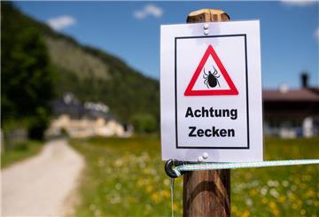 Ein Schild mit der Aufschrift "Achtung Zecken" steht vor einem Weg. Die Zeckengefahr steigt: Drei weitere Regionen sind jetzt FSME-Risikogebiete.
