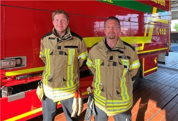Beide Feuerwehrmänner blicken in die Kamera.