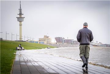 Blick Richtung Deich und Radarturm mit Spaziergängern während der Flut