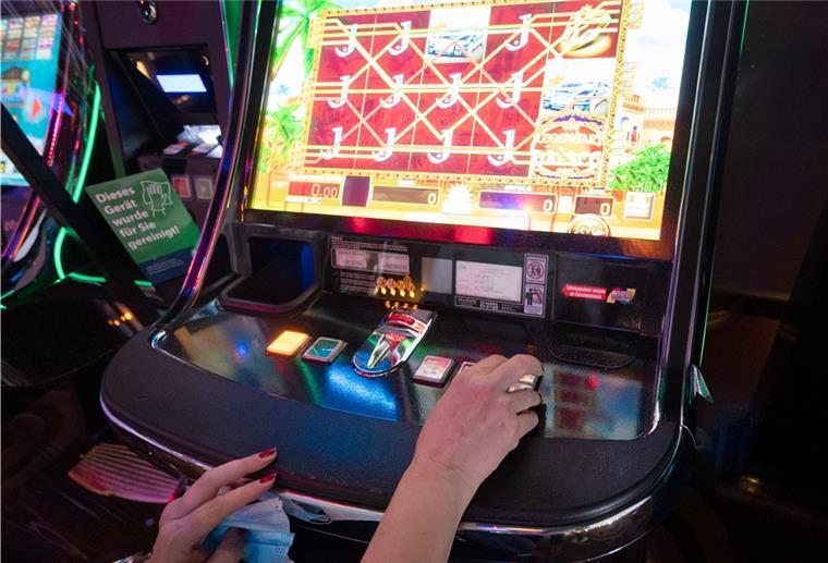 In die Spielhalle geht‘s erst mit 21 Eine Frau sitzt in einer Spielhalle vor einem Automatenspiel. S