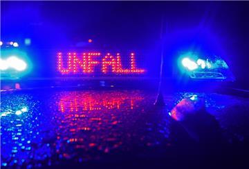 Ein Polizeiwagen mit Unfallschild und Blaulicht im Regen.