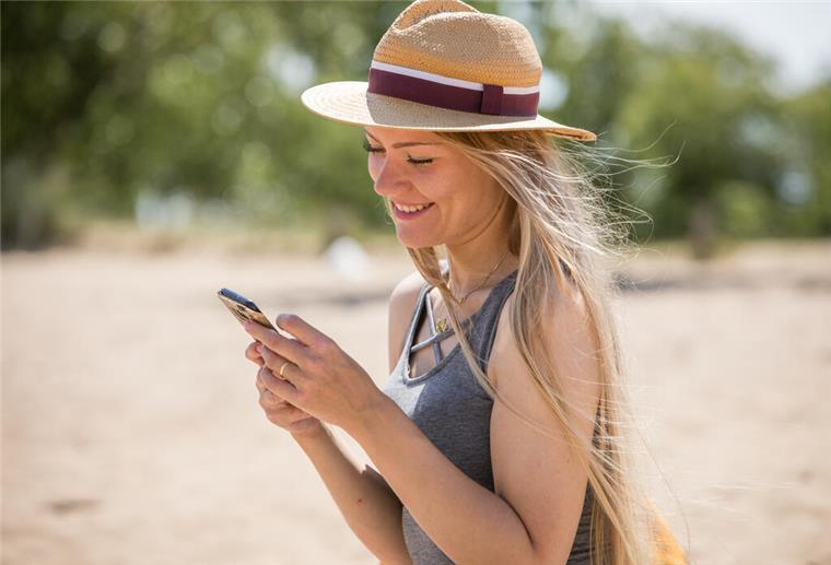 Hirnforscher: Ständige Urlaubs-Posts beeinträchtigen die Erholung Frau mit Handy am Strand