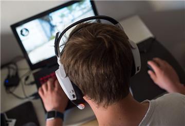 Ein Jugendlicher sitzt mit einem Headset vor einem Laptop