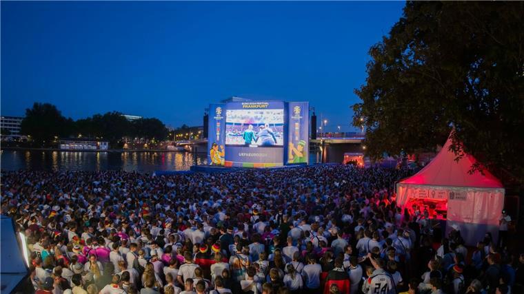 Fußballfans verfolgen ein EM-Spiel in der Fanzone am Mainufer.