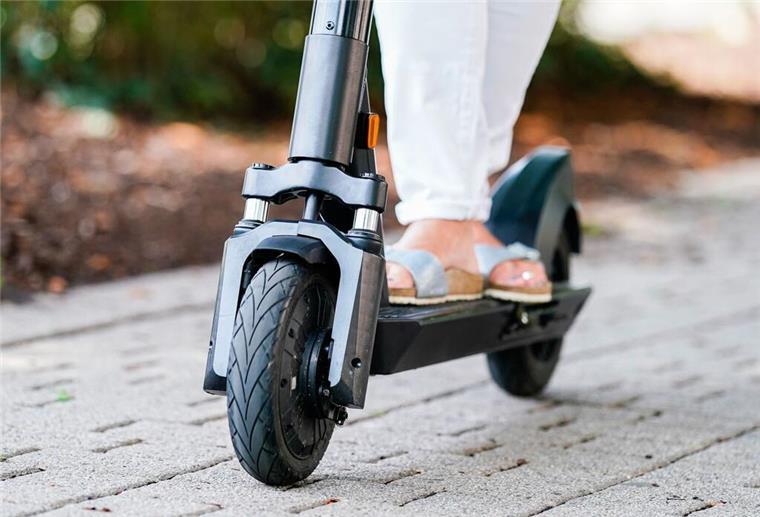 Die Füße einer Frau auf einem E-Roller.