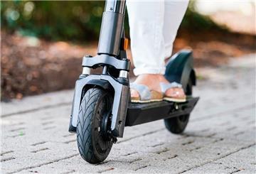 Die Füße einer Frau auf einem E-Roller.