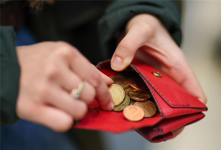 Eine Person hält eine rote Geldbörse in den Händen.