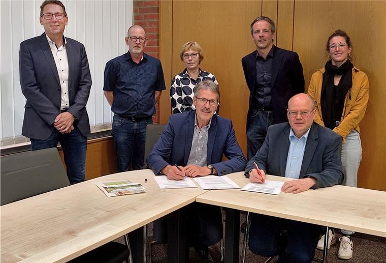 Schiffdorfer Wirtschaftswege auf dem Prüfstand Zwei Männer sitzen an einem Tisch und unterzeichnen Dokumente.