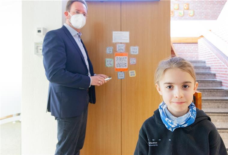 Nordholz: Kinder werben für Kinderrechte Gemeinsam mit Bürgermeister Marcus Itjen klebt der Viertklässler Karl die ersten QR-Codes mit den Kinderrechtsvideos gut sichtbar im Nordholzer Rathaus fest.