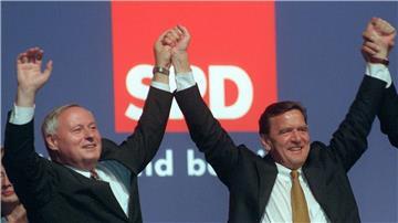 Gerhard Schröder (r) und Oskar Lafontaine halten sich bei einer Veranstaltung an den Händen.