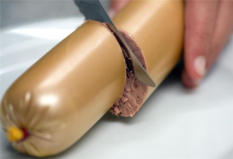  Eine Frau schneidet eine Leberwurst durch. 