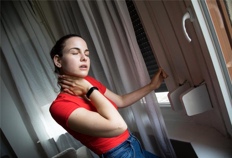Eine Frau lässt Rollläden herunter. Geschlossene Rollläden halten Sonnenstrahlung und Hitze draußen. So bleibt die Wohnung auch an heißen Tagen angenehm kühl.