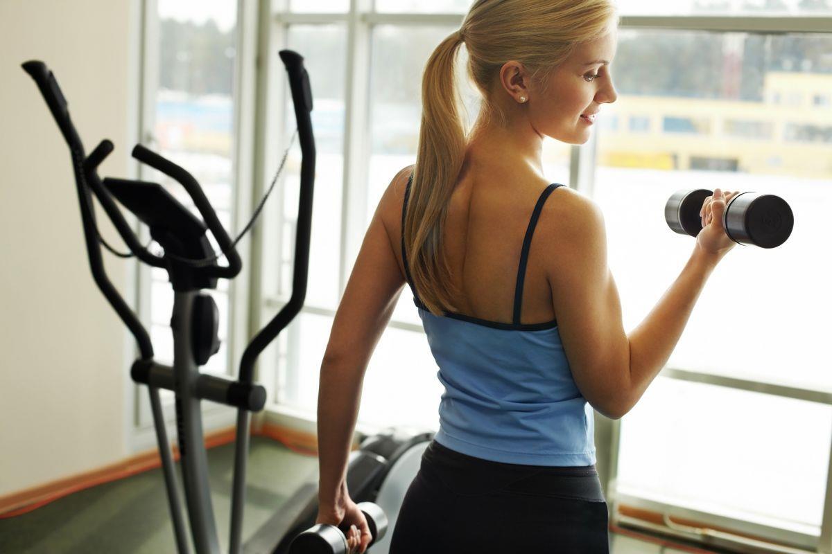 Sechs Tipps gegen Rückenschmerzen Frau mit Hanteln im Fitnessstudio