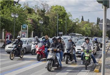 Autos und Motorräder warten im Zentrum von Athen an einer Verkehrsampel.  