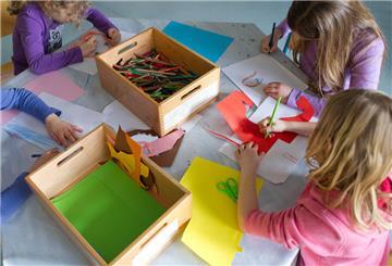 Grundschülerinnen sind in einem Kinderhort mit Bastelarbeiten beschäftigt.