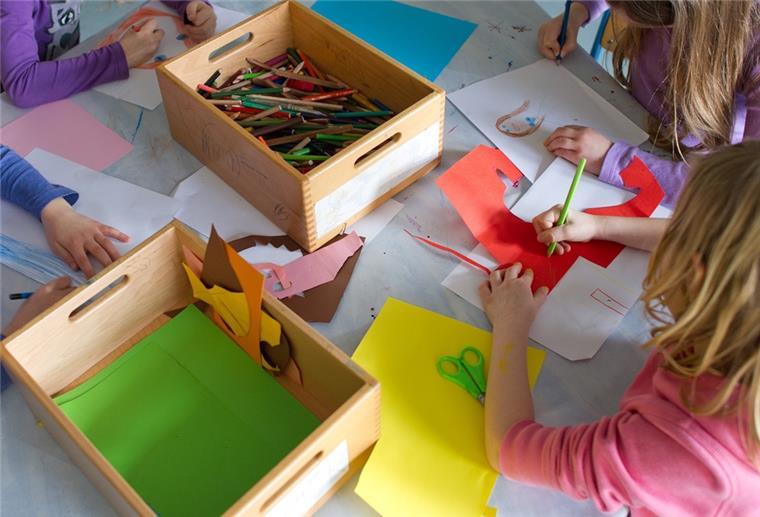 Kinder malen auf einem Tisch.
