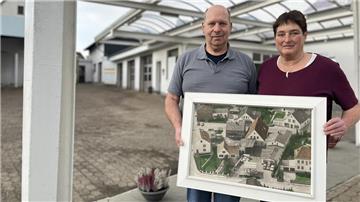 Zwei Menschen mit einem großen Bild in den Händen. 