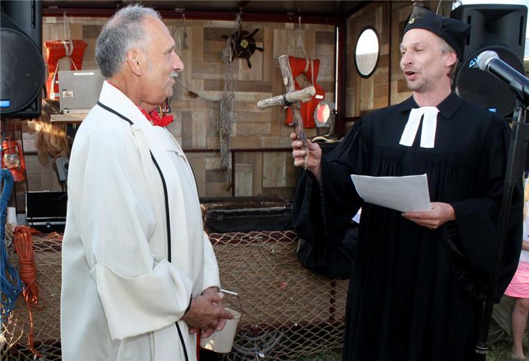 Hafenfest in Nartum: Party im "Kroatien des Nordens" Hafenpastor Florian Schwarz übergibt Treibholzkreuz und Urkunde an den frisch gekürten Nartumer Obersten Hafenministranten „Fredy“ Carstens.