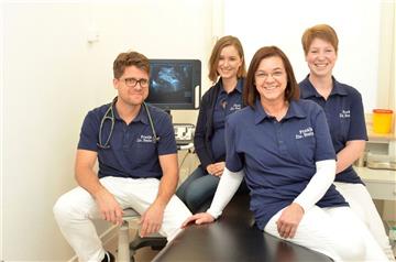 Hausarzt Dr. Florian Steiner mit seinen Mitarbeiterinnen Stefanie Hallerbach und Heike Kohne (von rechts) sowie seiner Frau Nana Steiner. Auf dem Ultraschallmonitor im Hintergrund ist zudem Ida zu sehen. Die Tochter der Steiners soll im Februar zur Welt kommen. 
