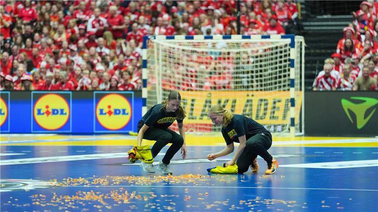 Helfer entfernen Konfetti, das ein Mann zuvor auf dem Handball-Feld verstreut hatte.