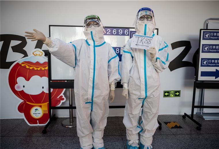 36 weitere Infizierte unter Olympia-Teilnehmern in Peking Helfer in kompletter Schutzmontur stehen am Flughafen Peking, um die mit speziellen Charterflugzeugen ankommenden Sportler, Delegationen und Journalisten zu den Olympischen Winterspielen 2022 zu begrüßen.