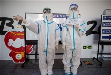 Helfer in kompletter Schutzmontur stehen am Flughafen Peking, um die mit speziellen Charterflugzeugen ankommenden Sportler, Delegationen und Journalisten zu den Olympischen Winterspielen 2022 zu begrüßen. 