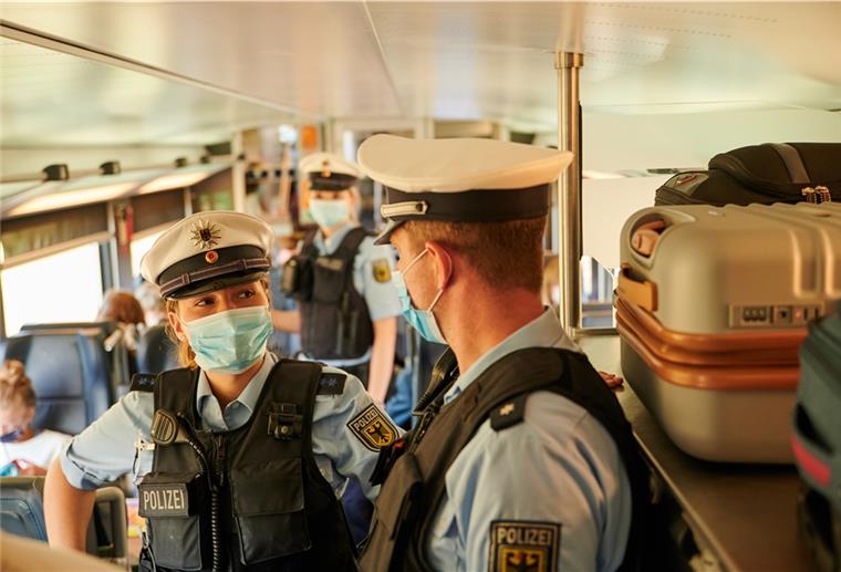Polizisten mit Gesichtsmasken in einem Zug.