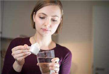 Eine Frau kippt Pulver in ein Glas.