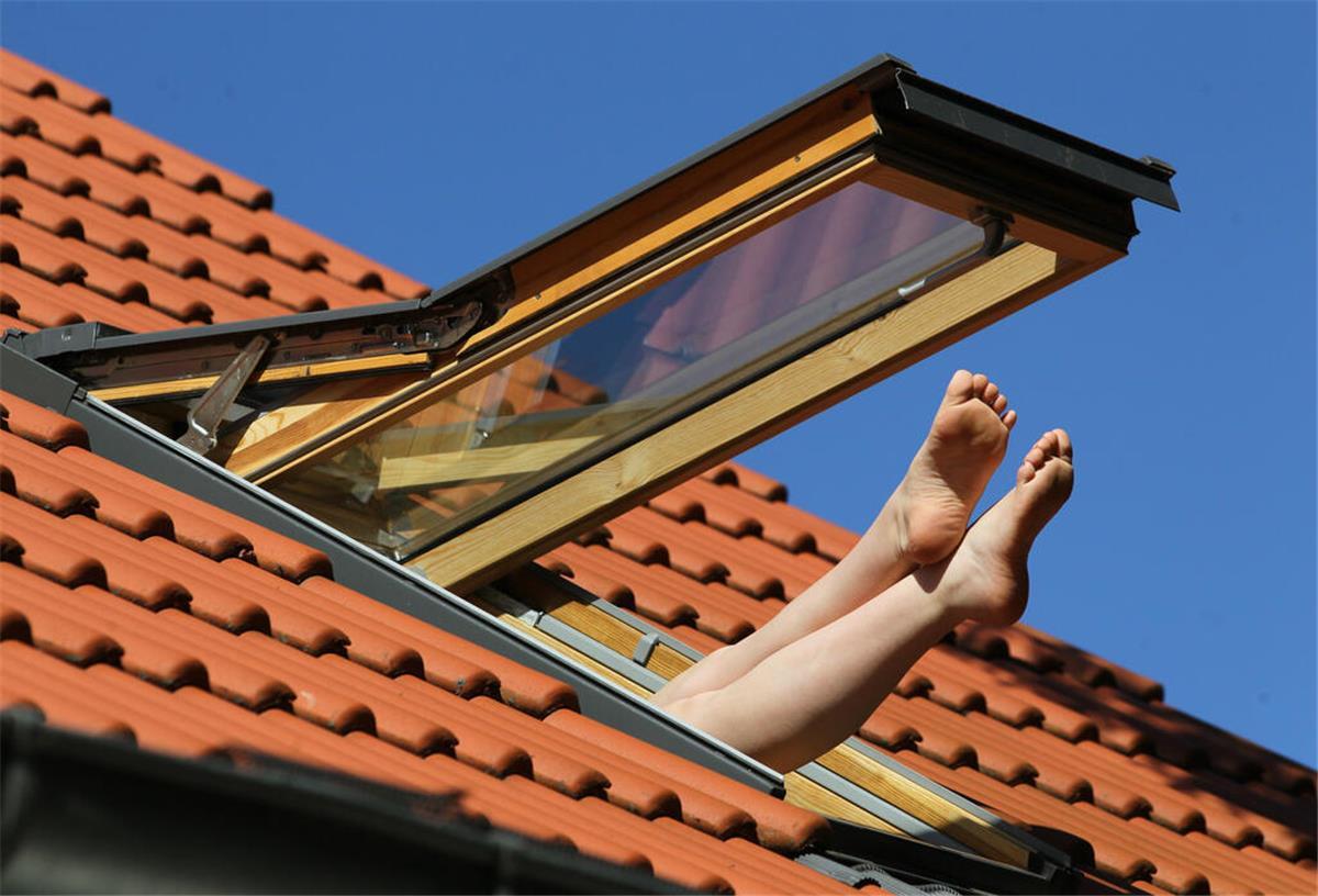 Genialer Trick: So kriegst Du die brütende Hitze aus Deiner Wohnung Eine Wohnung im Dachgeschoss mit offenem Fenster. Füße schauen heraus.