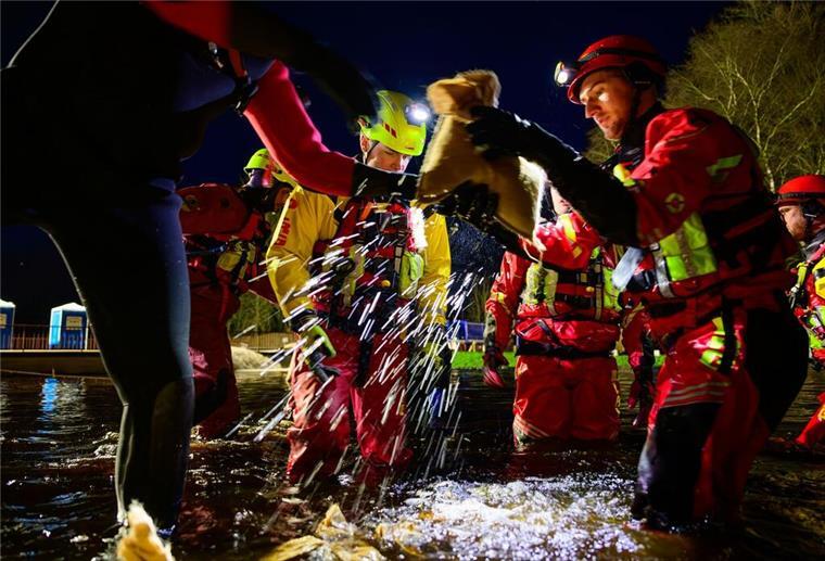 Ein Jahr nach dem Weihnachtshochwasser: DLRG schlägt Alarm Strömungsretter der DLRG sichern beim Weihnachtshochwasser um den Jahreswechsel 2023/2024 mit Sandsäcken einen Deich. (zu dpa: «Mehr Hilfe für die Helfer»)