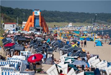 Touristen sind bei sonnigem Wetter im Ostseebad Zinnowitz am Strand unterwegs.
