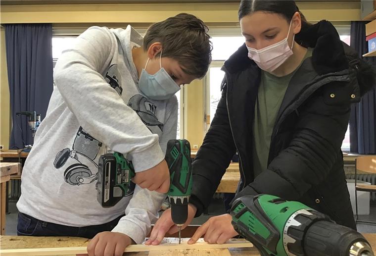 Bremerhavener Schüler bauen selbst Instrumente Holzarbeit: Amira Zertal (13) unterstützt Liam Brokmann (13) bei der Herstellung des Bogens, auf dem später die Musiksaite befestigt wird.