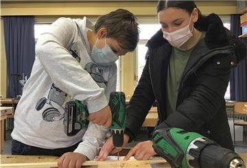Holzarbeit: Amira Zertal (13) unterstützt Liam Brokmann (13) bei der Herstellung des Bogens, auf dem später die Musiksaite befestigt wird.