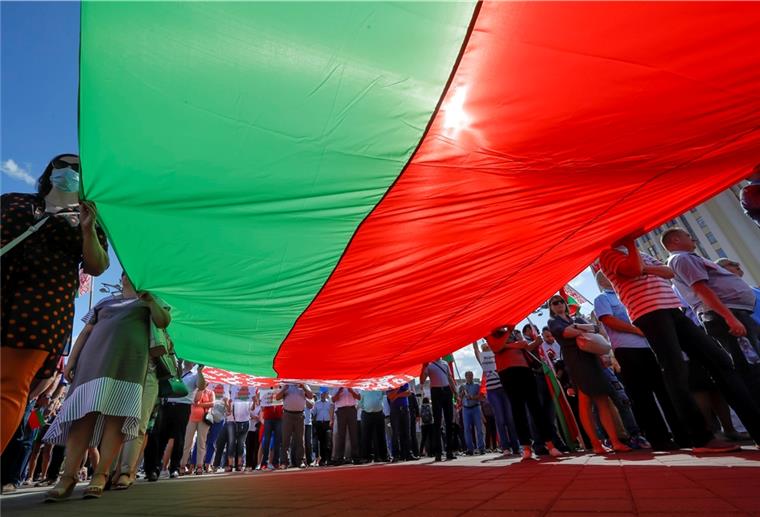 Massenproteste in Belarus: Lukaschenko bleibt hart Hunderte Anhänger von Präsident Lukaschenko versammeln sich zu einer Kundgebung auf dem Unabhängigkeitsplatz in Minsk und halten eine riesige Nationalflagge.