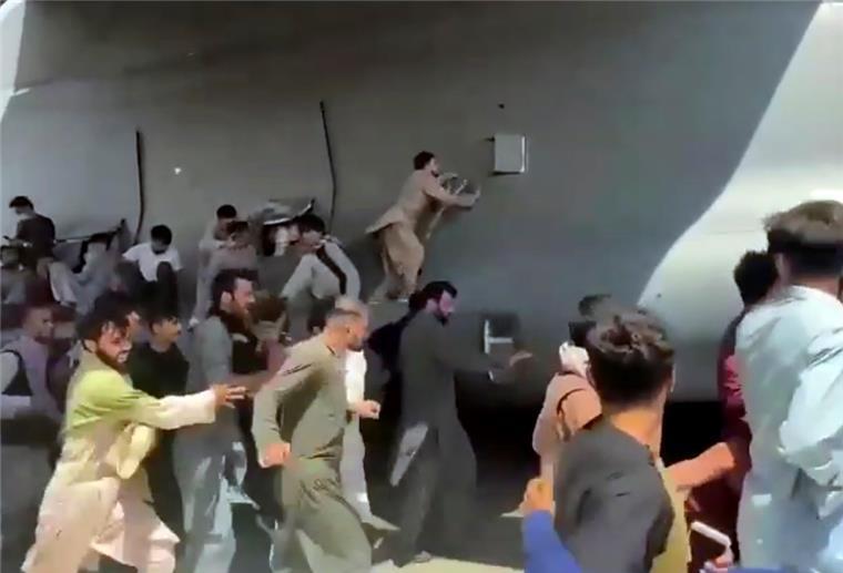 Hunderte Menschen laufen neben einer Boeing C-17 der United States Air Force, die auf dem Rollfeld des Kabul International Airport fährt. Zahlreiche Afghanen, die sich nach der Machtübernahme der Taliban in Sicherheit bringen wollen, versuchten auf dem Flughafen in Flugzeuge.
