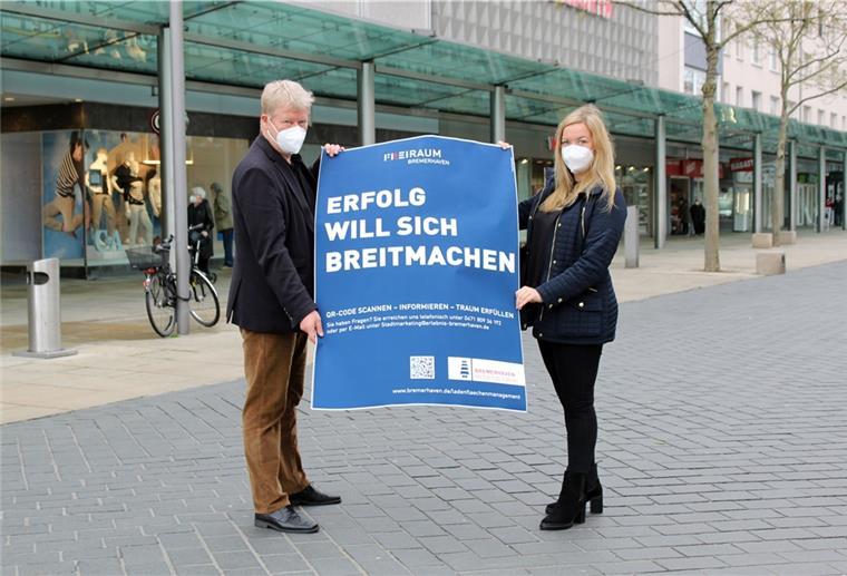 Bremerhaven: Plakate in leeren Schaufenstern Ideen fürs Ladenflächenmanagements in der Bremerhavener Innenstadt: Dr. Ralf Meyer und Laura Kottsieper präsentieren ein Plakat zur aktuellen Aktion.