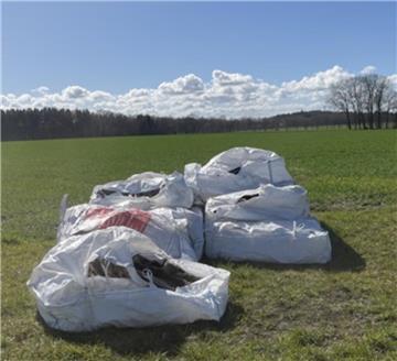 Sechs weiße Big-Bags liegen auf einer grüner Wiese. Es handelt sich um einen Fall illegaler Müllentsorgung. 