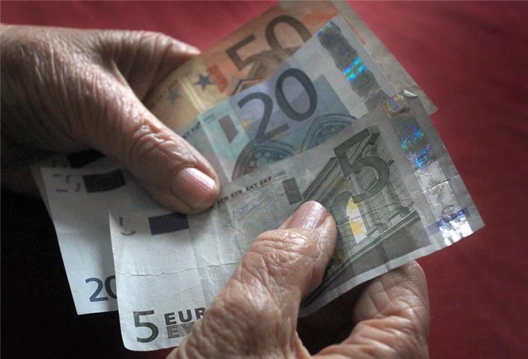 Eine ältere Frau hält verschiedene Euronoten in der Hand.